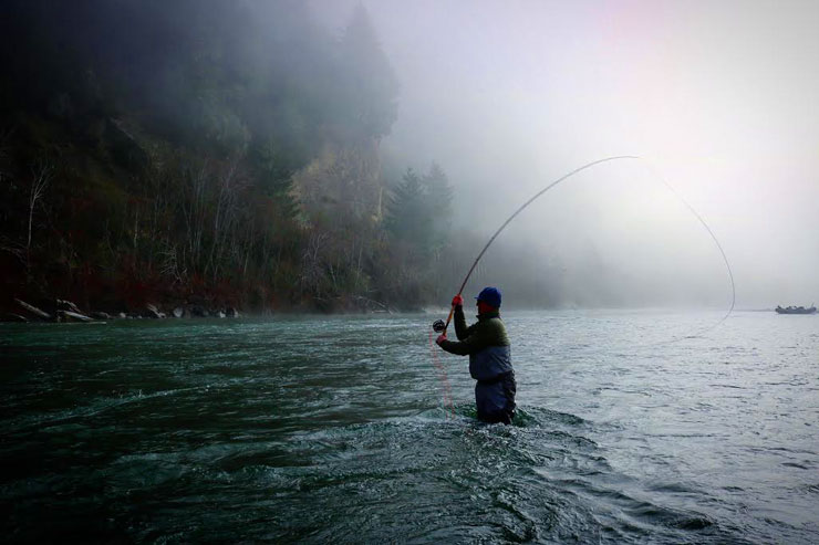 An angler spey casting on a coastal river